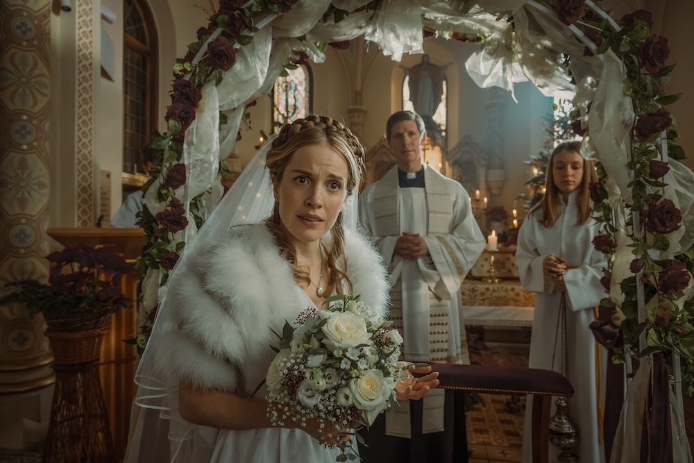 A woman in a wedding dress is standing in front of an alter in a beautiful church, looking at the camera bewildered