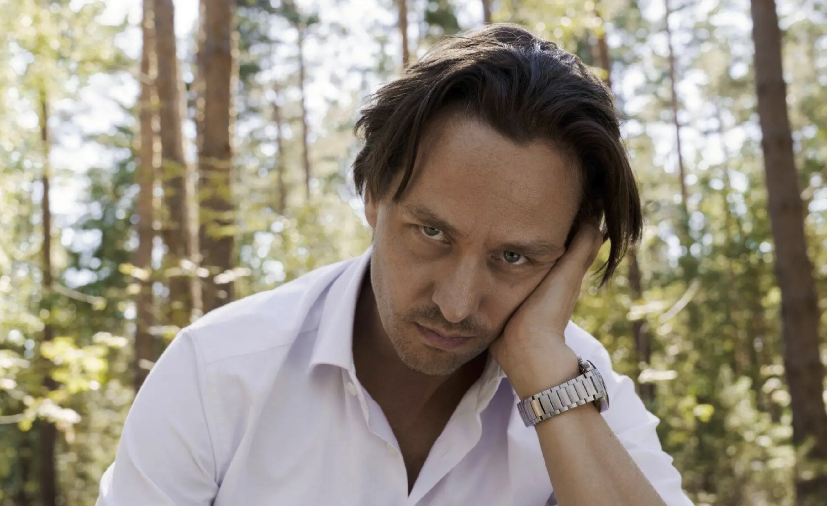 A man (main character Björn Diemel) is resting his head on his hand and looking directly at the camera in a bored and dissatisfied way