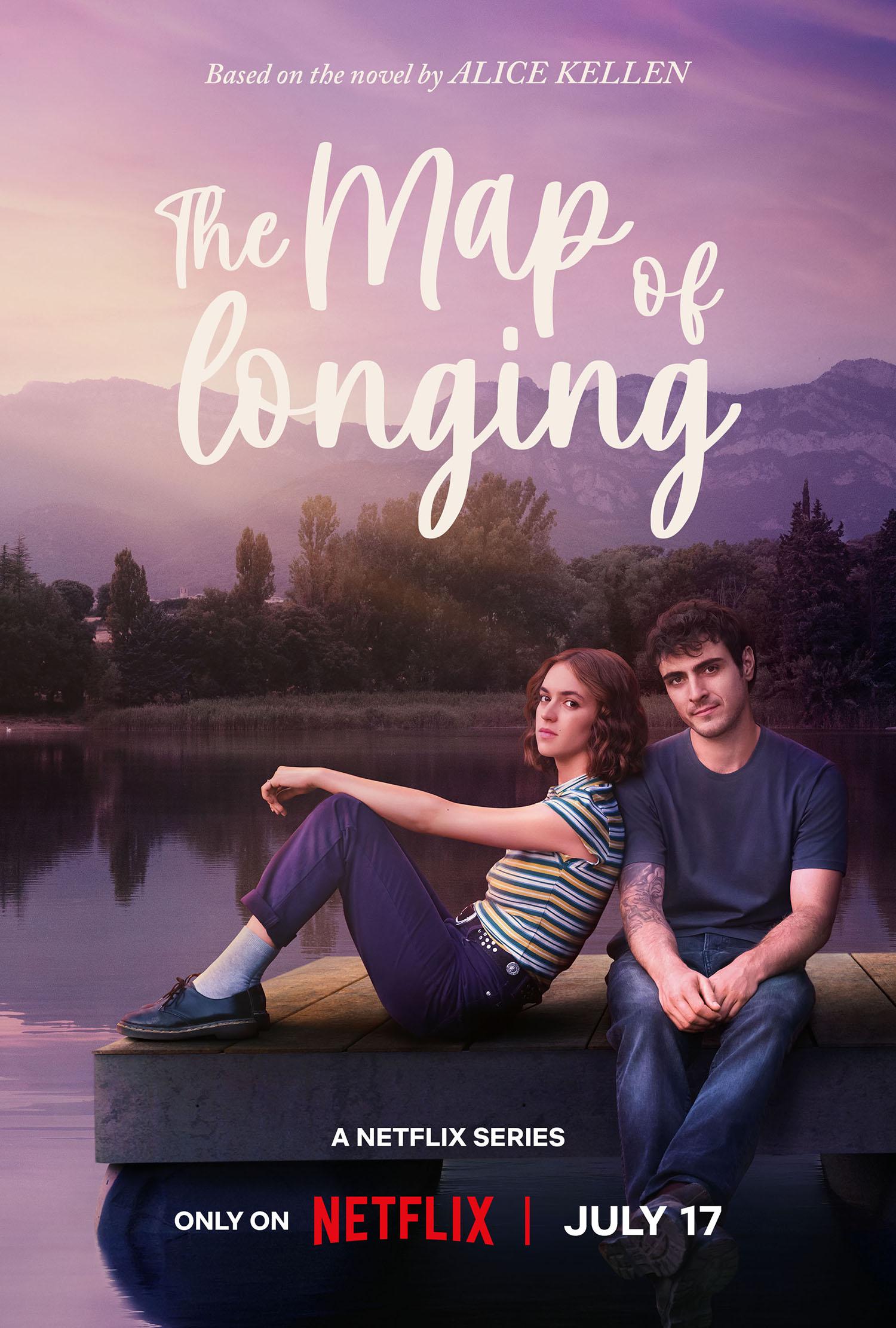 A young couple is sitting by a lake, the purple sky reflecting in the water, she is leaning on him, and both are looking directly at the camera