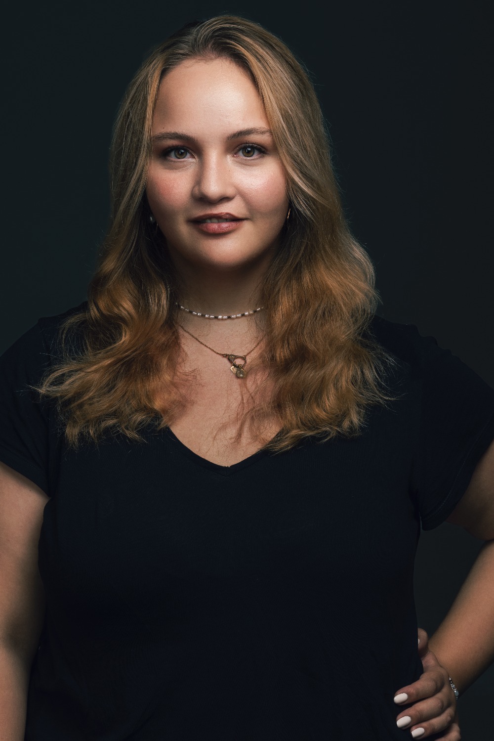 Melanie Benedikter smiles at the camera with one arm on her hip.