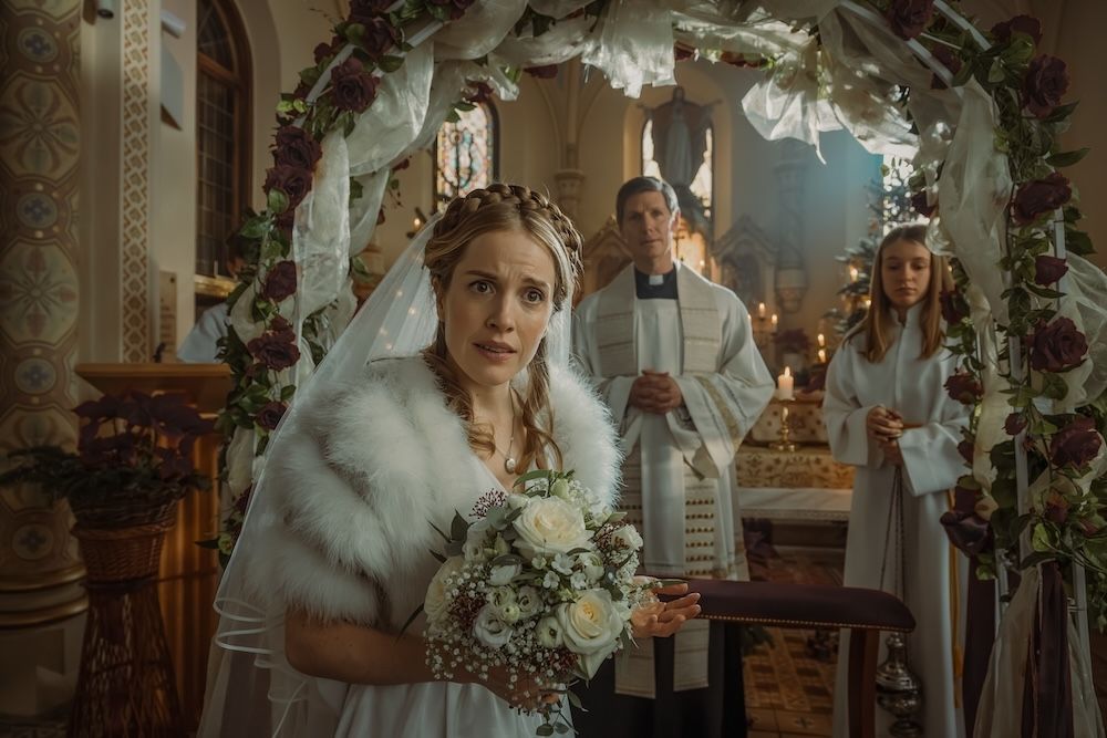A woman in a wedding dress is standing in front of an alter in a beautiful church, looking at the camera bewildered